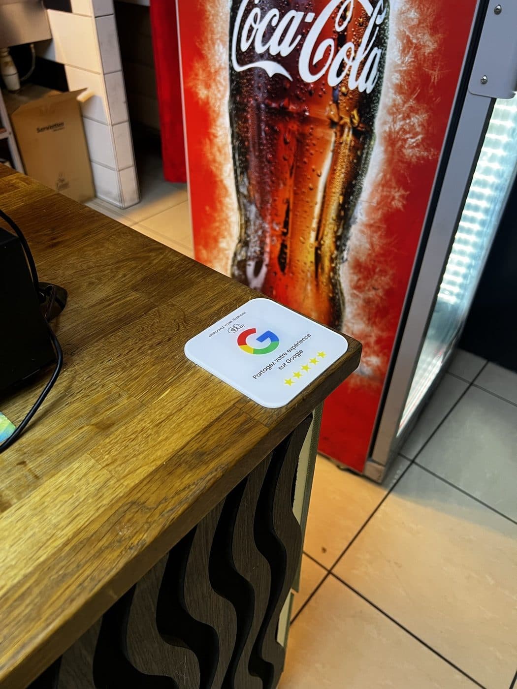 Plaque Avis Google posée sur le comptoir en bois d'un restaurant